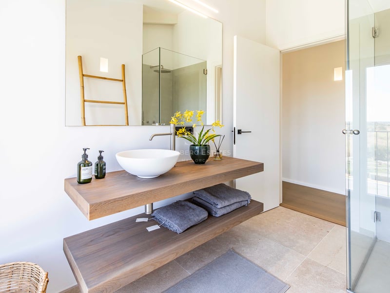 Minimalist bathroom featuring a floating double-tier oak vanity, white vessel sink, and large wall-mounted mirror.