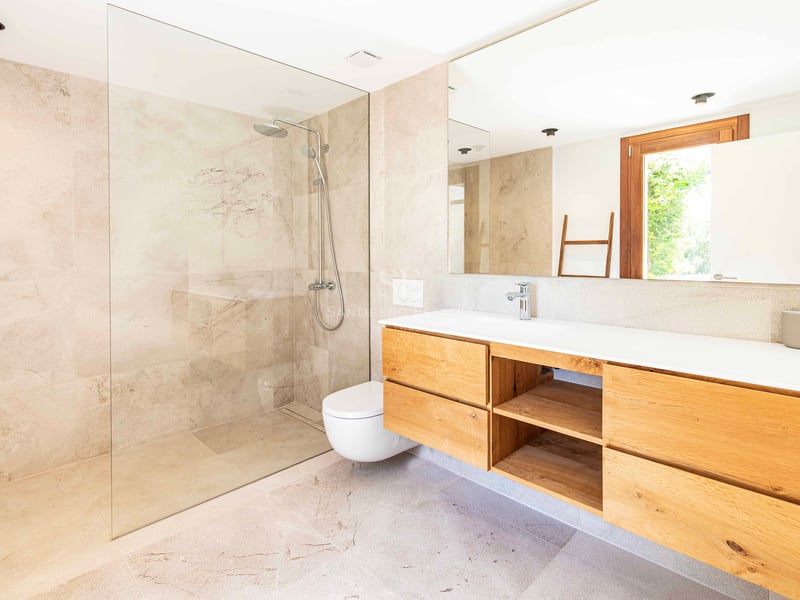 Salle de bain moderne avec douche à l'italienne, paroi en verre, meuble vasque en chêne et carrelage en pierre beige.