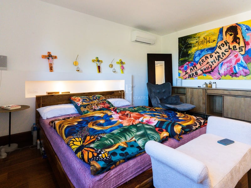 Chambre lumineuse dotée d'un lit avec une literie florale colorée, une grande œuvre d'art moderne et un éclairage encastré.