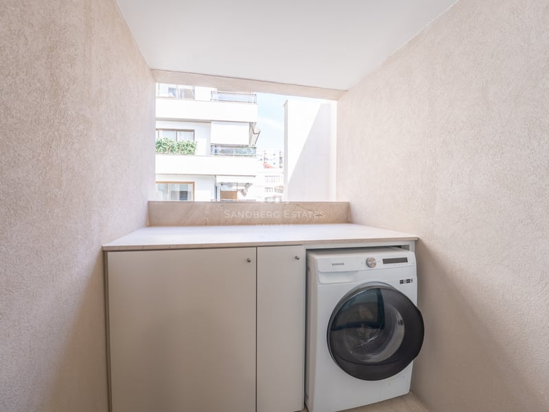 Lave-linge et placards blancs encastrés dans un coin de balcon aux murs beiges texturés.