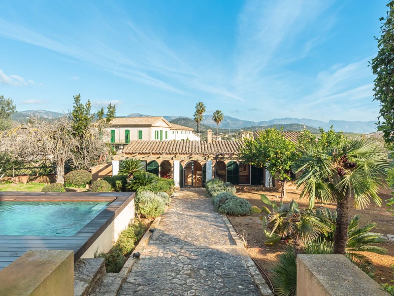 Piscine extérieure et chemin de pierre menant à une villa méditerranéenne avec vue sur les montagnes.