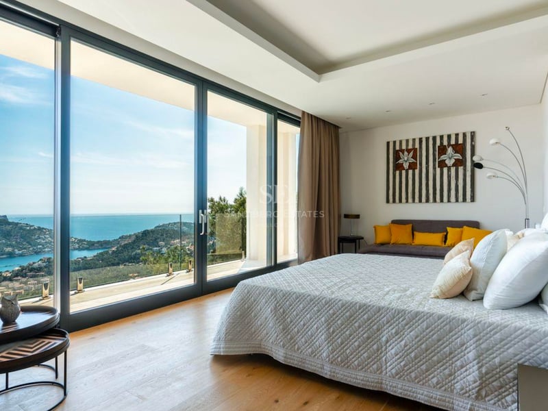 Chambre moderne avec de grandes baies vitrées offrant une vue imprenable sur la mer et la côte.