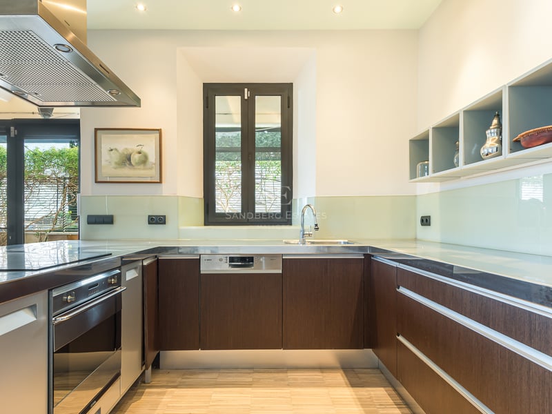 Cuisine moderne avec des armoires en bois foncé, des plans de travail en inox et une crédence en verre.