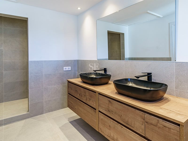 Salle de bains contemporaine avec carrelage gris, meuble en bois, vasques noires et douche à l'italienne.