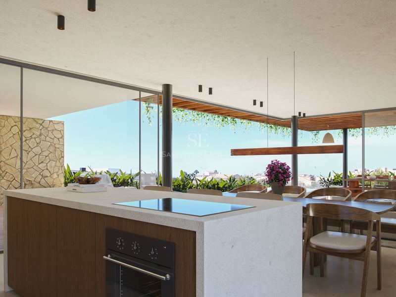 Îlot de cuisine luxueux en pierre, salle à manger en bois et baies vitrées ouvrant sur une terrasse.