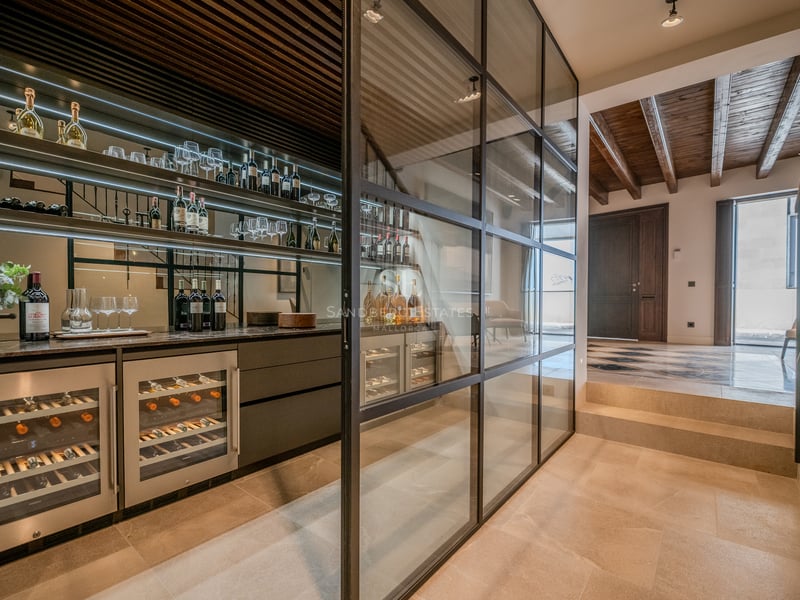 Cave à vin moderne avec parois en verre, cadres noirs, éclairage intégré et armoires à vin professionnelles.