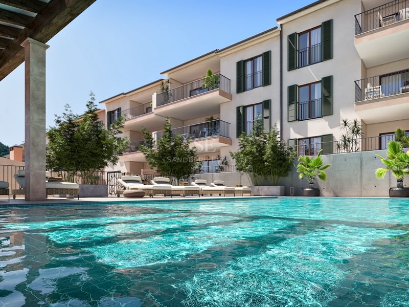 Sparkling turquoise swimming pool with lounge chairs in front of a multi-story Mediterranean apartment building.