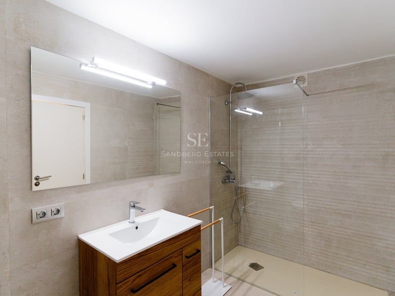 Salle de bain contemporaine avec douche à l'italienne, carrelage en pierre et meuble en bois avec grand miroir.