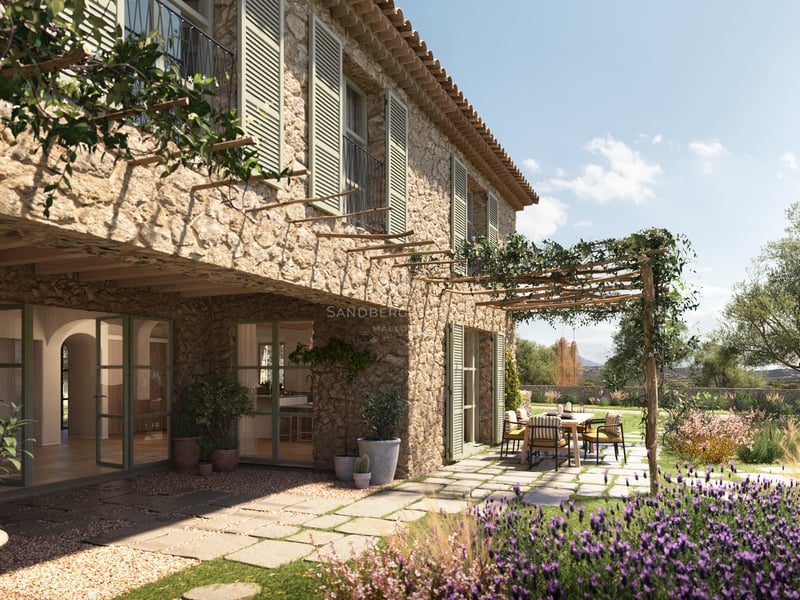 Maison en pierre avec volets verts, pergola en bois avec coin repas extérieur et lavande en fleur.