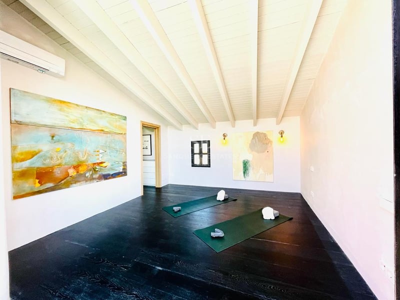 Salle de yoga minimaliste avec parquet sombre, plafond à poutres blanches et art abstrait sur les murs.
