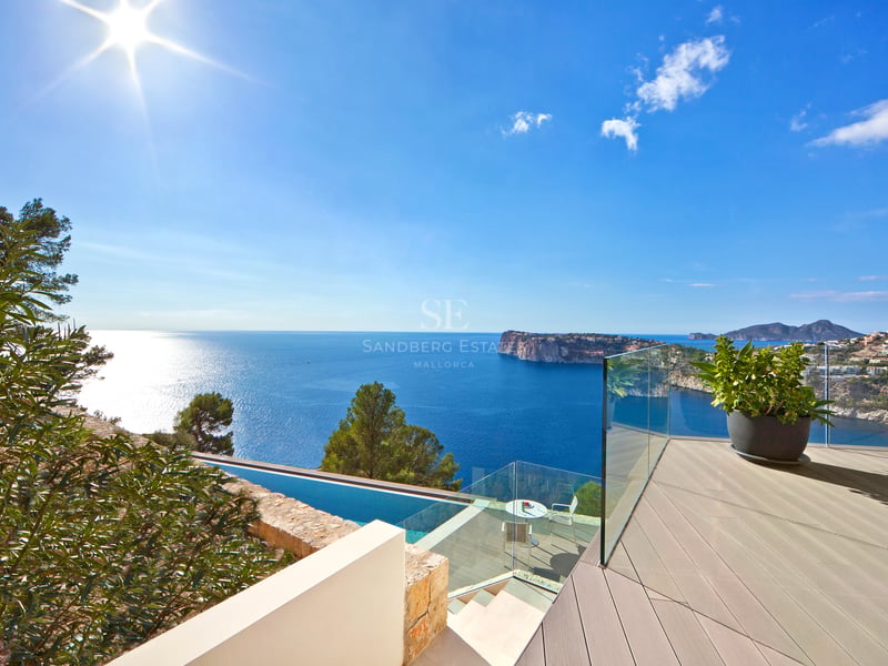 Terrasse moderne avec garde-corps en verre surplombant la mer Méditerranée et une piscine à débordement.