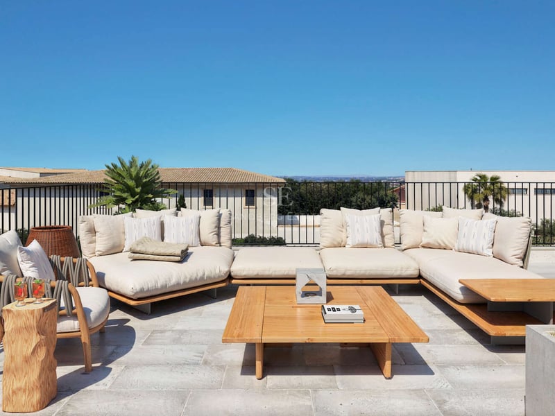 Terrasse ensoleillée avec grand canapé d'angle crème, table basse en bois et sol en pierre naturelle.