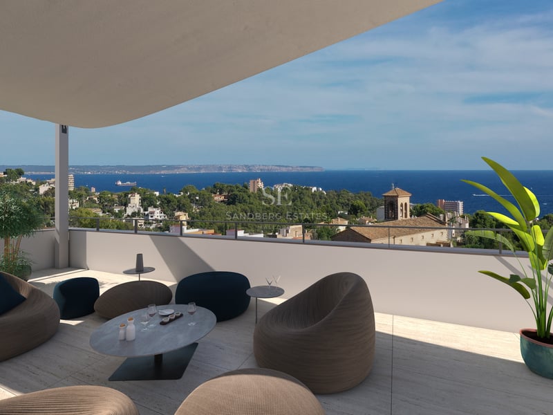 Terrasse moderne sur le toit avec sièges design offrant une vue sur une ville côtière méditerranéenne et la mer.