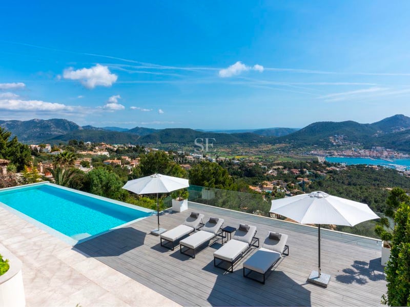 Terrasse extérieure avec piscine bleue, bains de soleil modernes, parasols blancs et vue sur les montagnes et la mer.