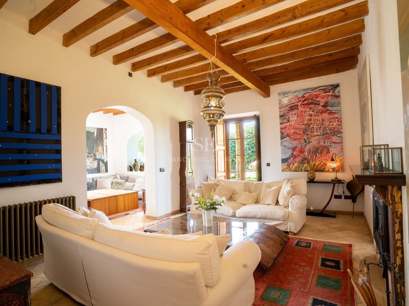 Salon avec canapés blancs, hauts plafonds à poutres et lanterne traditionnelle dans une villa méditerranéenne.