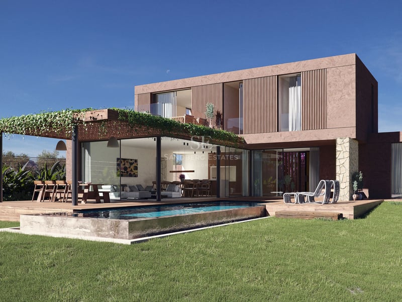 Villa contemporaine avec façade terracotta, piscine à débordement, terrasse en bois et baies vitrées sous un ciel bleu.