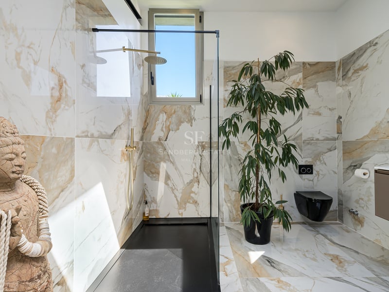 Salle de bain contemporaine avec carrelage en marbre blanc, douche à l'italienne et statue décorative zen.