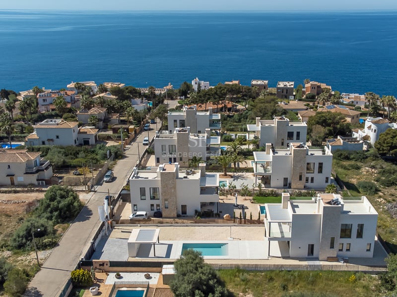 Vue aérienne d'un ensemble de villas blanches modernes avec piscines surplombant la mer Méditerranée.