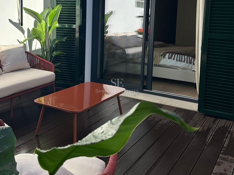 Terrasse privée avec mobilier terre cuite, plancher en bois et volets verts près de l'entrée de la chambre.
