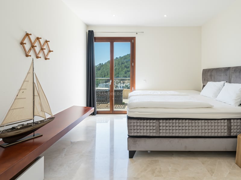 Chambre lumineuse avec sol en marbre, lit en velours gris et porte vitrée offrant une vue sur la montagne.