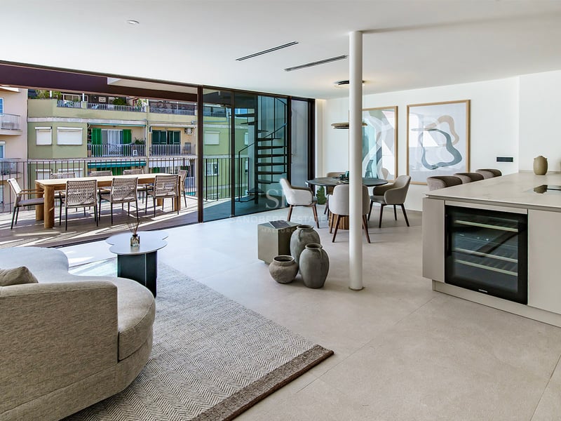 Salon contemporain lumineux avec îlot de cuisine, coin repas et une grande terrasse avec mobilier extérieur.