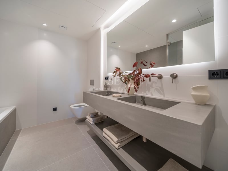 Salle de bain minimaliste avec double vasque flottante grise, grand miroir rétroéclairé et robinetterie murale.