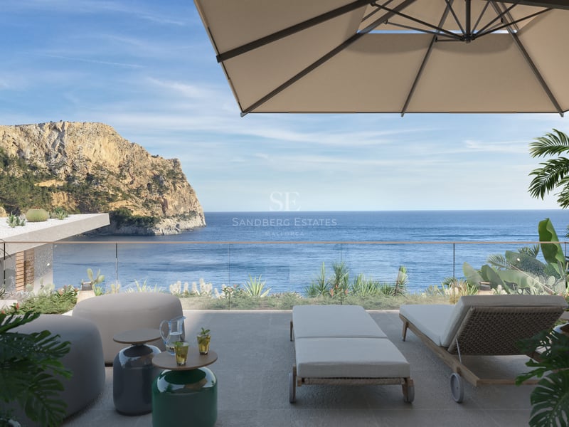 Terrasse ensoleillée avec chaises longues, parasol et garde-corps en verre surplombant la mer et une falaise.
