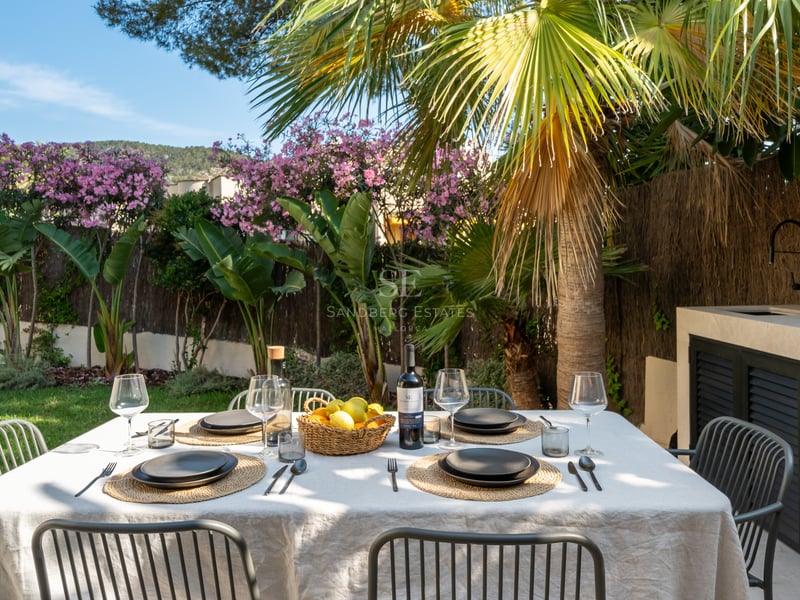 Table à manger extérieure pour six dans un jardin tropical à côté d'une cuisine d'été moderne en pierre.