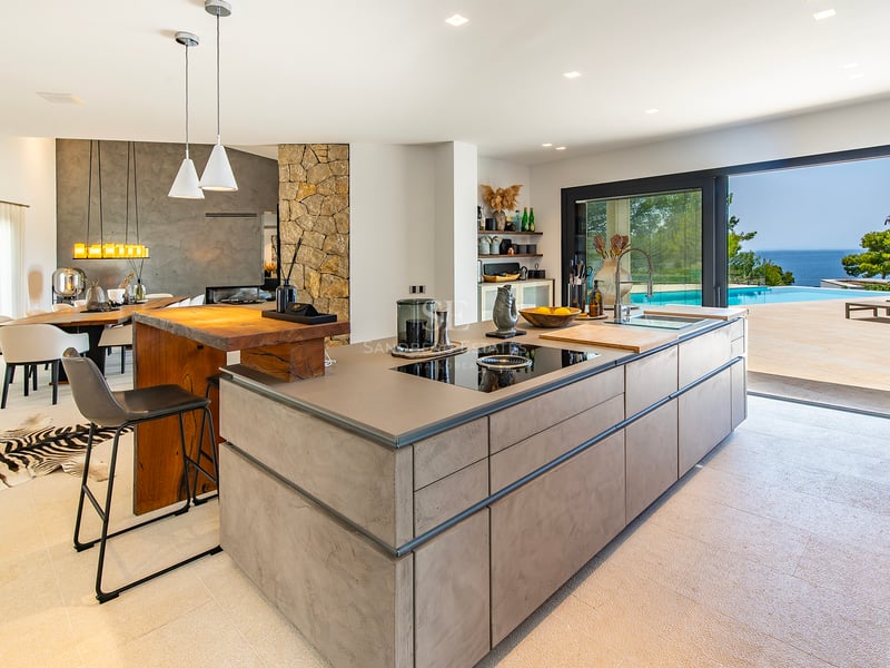 Vue extérieure d'une villa moderne avec piscine à débordement, végétation luxuriante et design architectural contemporain. Éclairage doux et ambiance luxueuse.