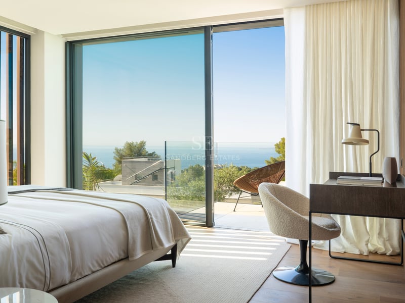 Chambre de maître moderne avec parquet, baies vitrées et terrasse offrant une vue sur la Méditerranée.