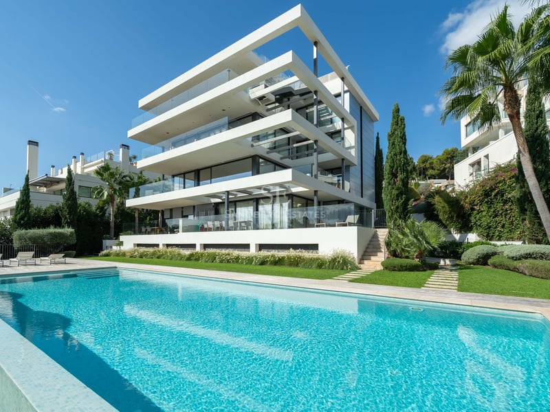 Vue extérieure d'une villa moderne à plusieurs niveaux avec une grande piscine turquoise et un jardin paysager.