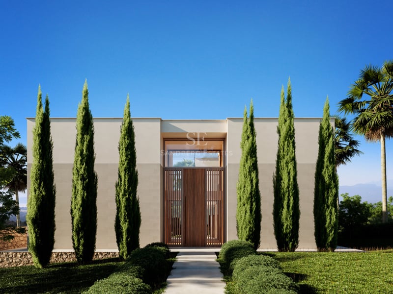 Entrée symétrique d'une villa moderne avec de grands cyprès, une porte en bois et un ciel bleu clair.