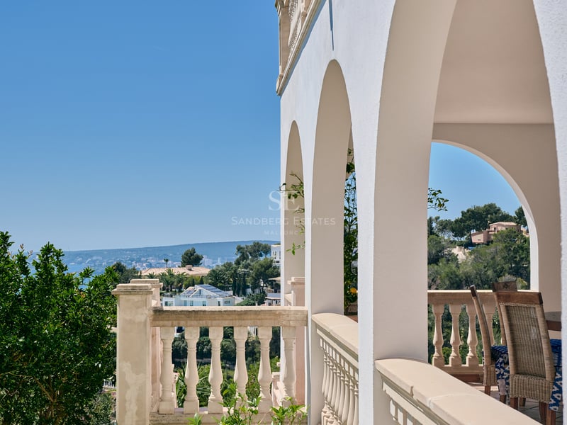 Terrasse à arches blanches et balustrade en pierre surplombant la côte et la mer Méditerranée.