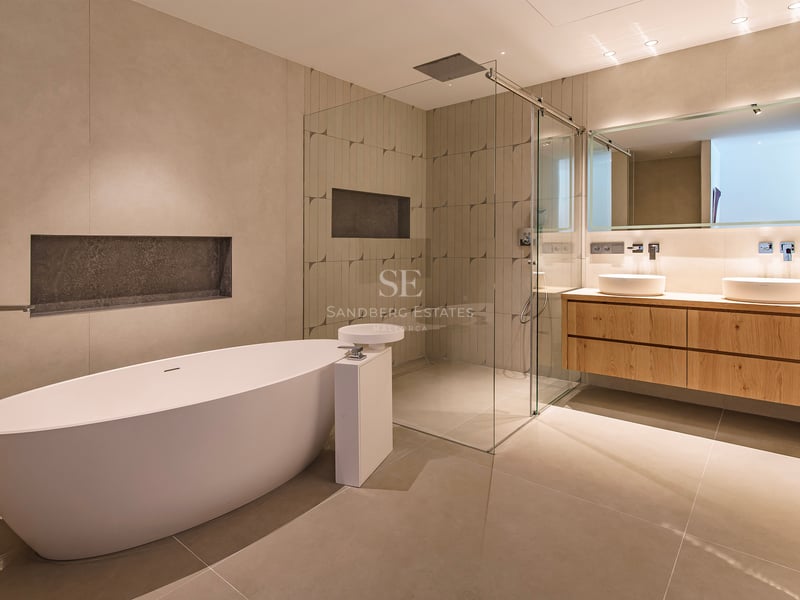 Salle de bains moderne avec baignoire îlot blanche, douche à l'italienne vitrée et double vasque en chêne.