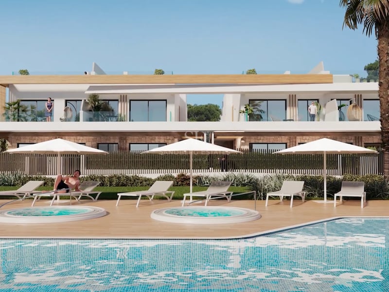 Modern outdoor pool area with two hot tubs, sun loungers under white umbrellas, and white residential building behind.
