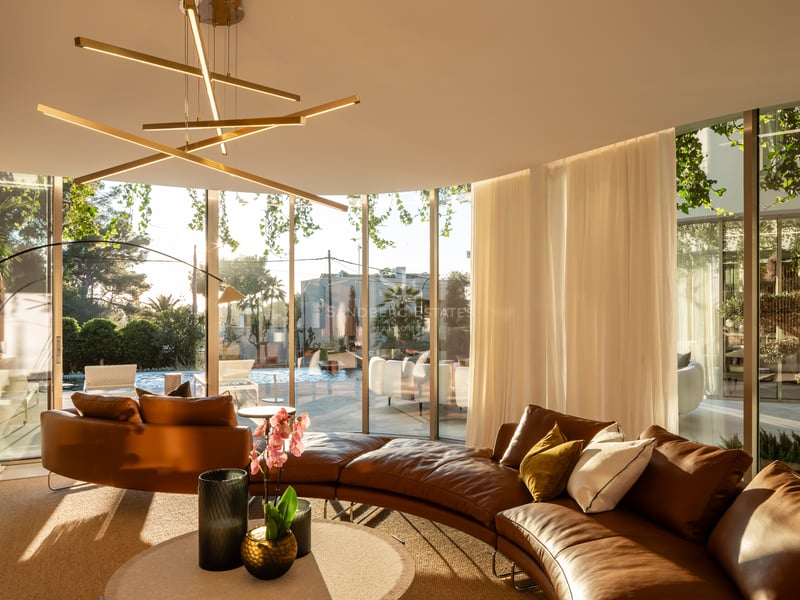 Salon luxueux avec canapé incurvé en cuir, luminaire design et grandes baies vitrées donnant sur la piscine.