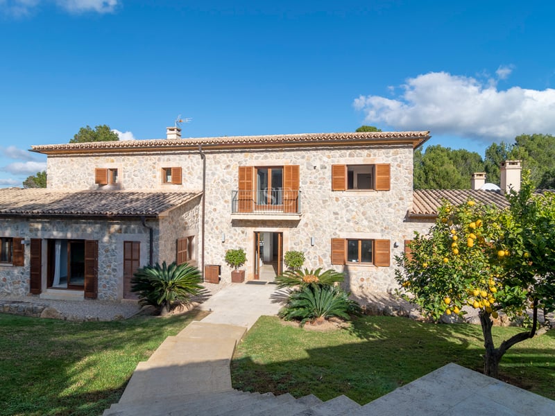 Villa de deux étages en pierre naturelle avec volets en bois marron, toit en terre cuite et un citronnier.