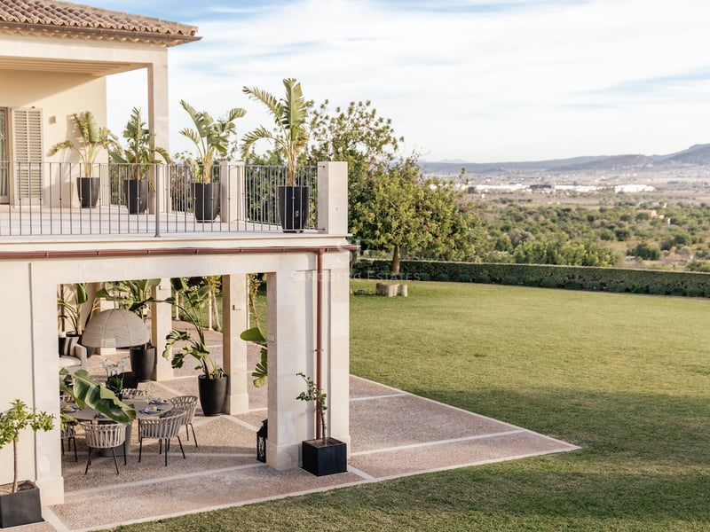 Terrasse en pierre sur deux niveaux avec coin repas extérieur, surplombant un grand jardin et des collines.