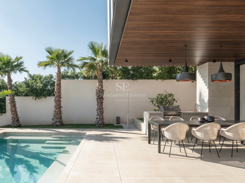 Terrasse moderne avec piscine turquoise, coin repas extérieur et plafond en bois avec suspensions design.
