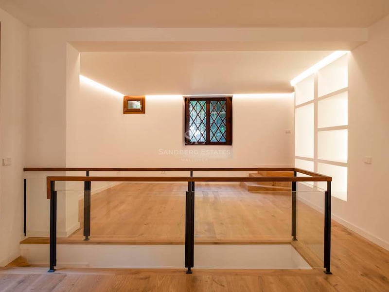 Palier intérieur moderne avec parquet en chêne clair, garde-corps en verre et éclairage indirect chaleureux.