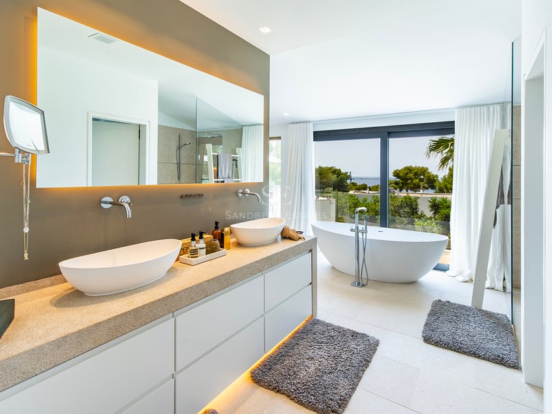 Vue extérieure d'une villa moderne avec piscine réfléchissante, larges fenêtres et design minimaliste dans des tons neutres.