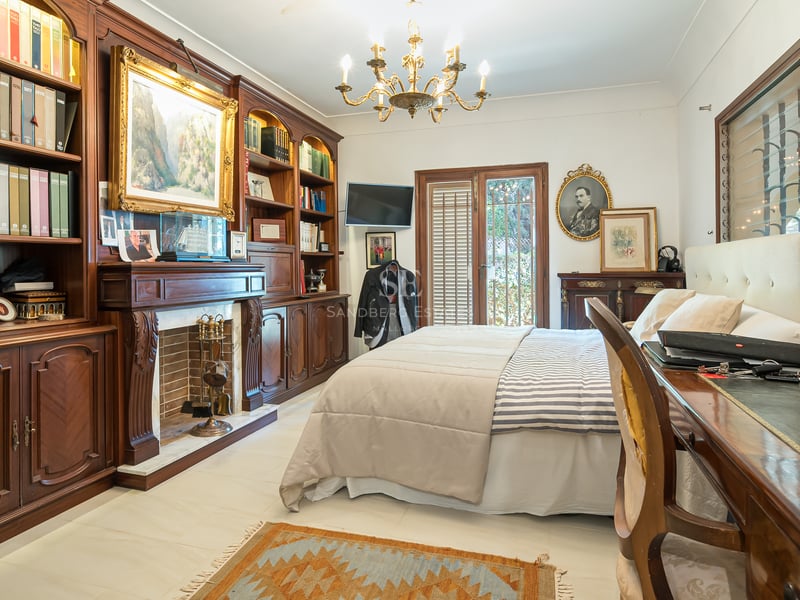 Chambre élégante avec bibliothèques en bois sombre, cheminée traditionnelle et lustre doré.