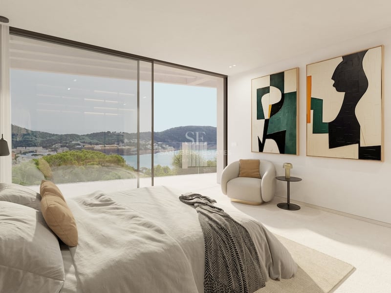 Chambre de maître moderne avec de grandes baies vitrées offrant une vue sur la côte et la mer.