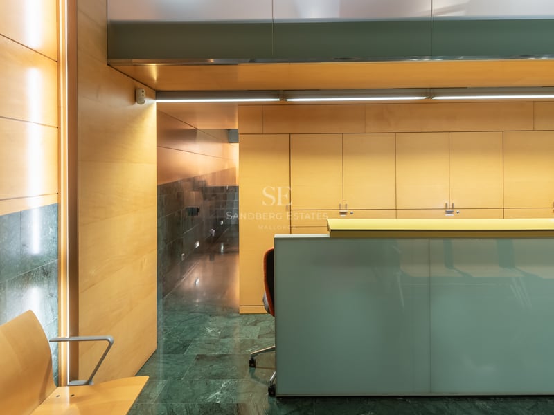 Modern reception desk with frosted glass, wood-paneled walls, and dark green marble flooring in a luxury building.