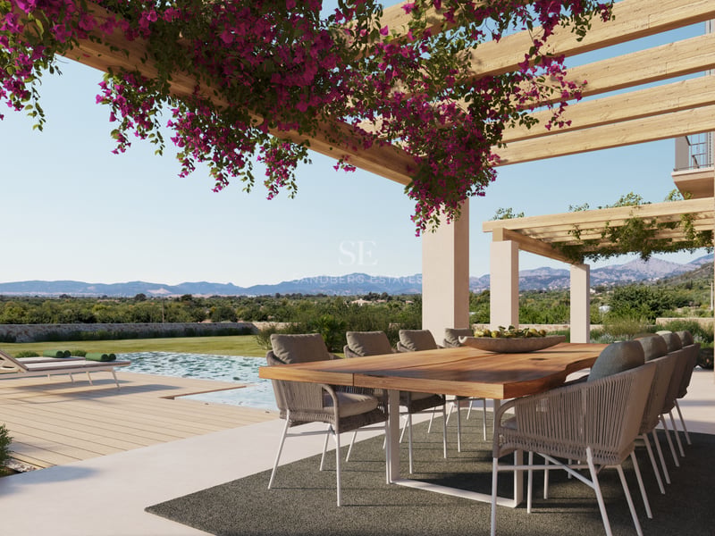 Table à manger en bois sous une pergola de bougainvilliers surplombant une piscine et des montagnes.