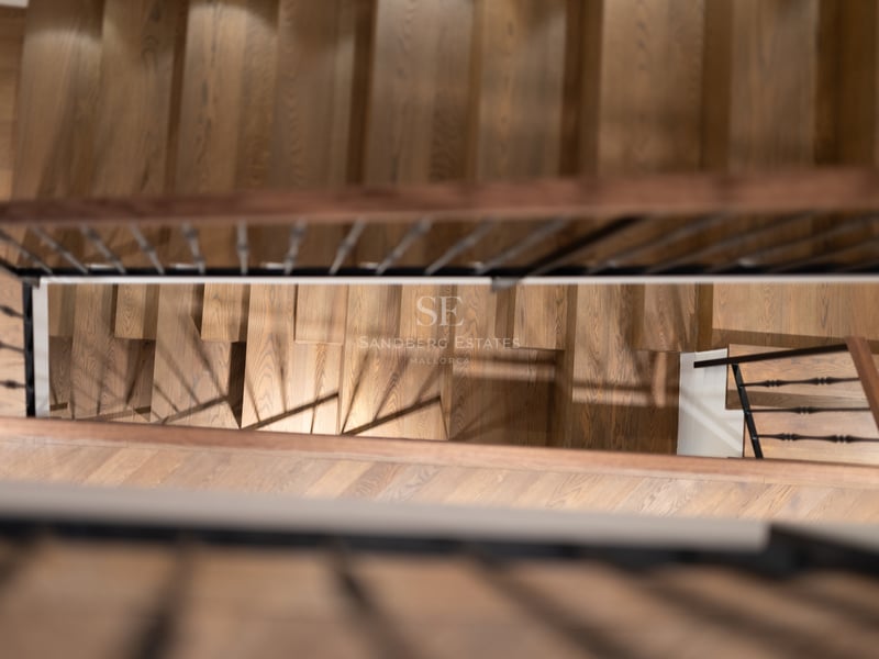Vue de dessus d'un escalier en bois de chêne avec une rampe en fer forgé noir dans une propriété de luxe.