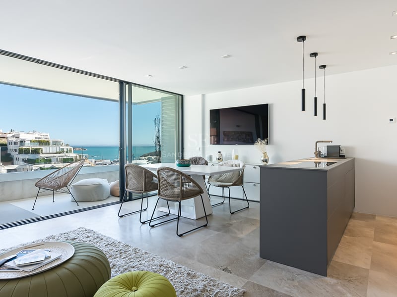 Espacio abierto con comedor, cocina y ventanales de suelo a techo con vistas al mar y terraza.