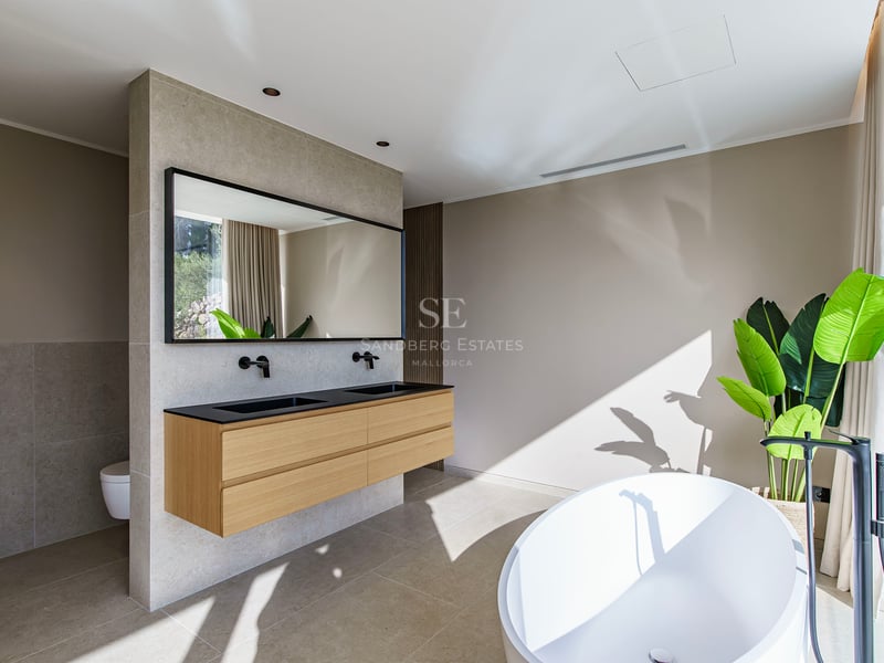 Salle de bain principale spacieuse avec baignoire blanche, double vasque suspendue en bois et robinetterie noire.
