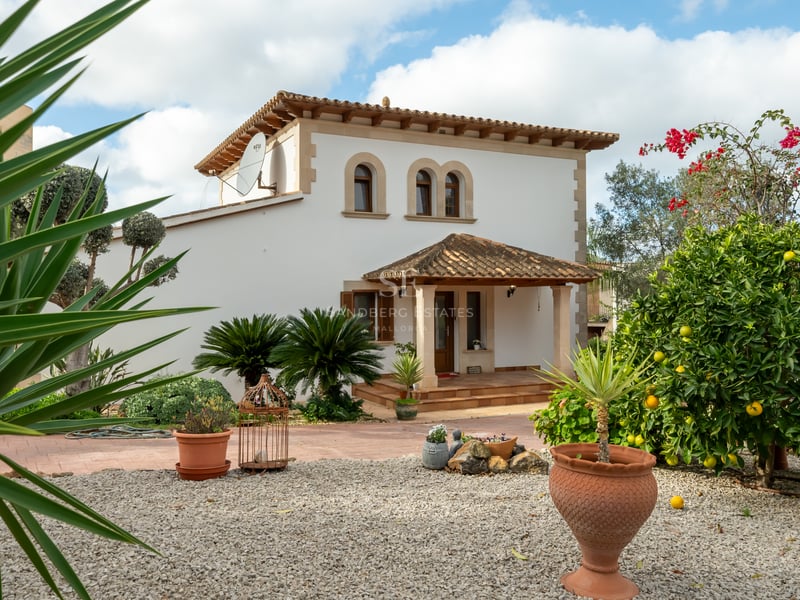 Villa blanche à deux étages avec toit en terre cuite, fenêtres cintrées et jardin avec citronniers.