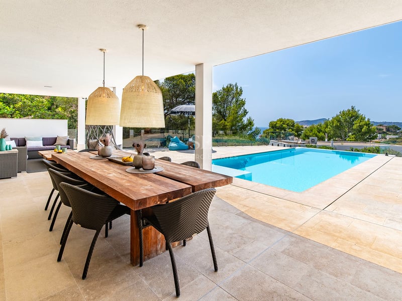 Salon spacieux avec baies vitrées, canapés beiges et table basse en bois. Vues panoramiques sur la mer depuis le balcon. Design moderne et lumineux.